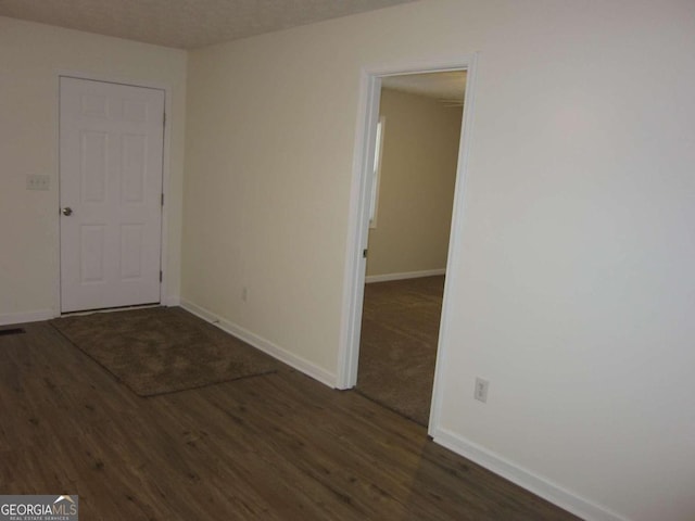 spare room with a textured ceiling and dark wood-type flooring