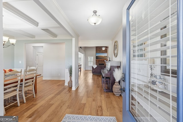 entryway with ornamental molding, hardwood / wood-style flooring, beamed ceiling, and a large fireplace