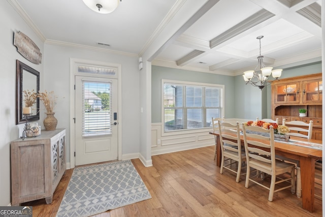 interior space featuring coffered ceiling, ornamental molding, beamed ceiling, and light hardwood / wood-style floors