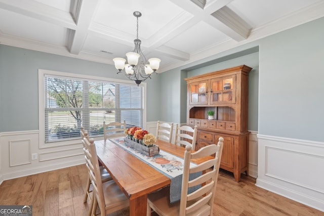 dining space with a notable chandelier, coffered ceiling, crown molding, light hardwood / wood-style flooring, and beam ceiling