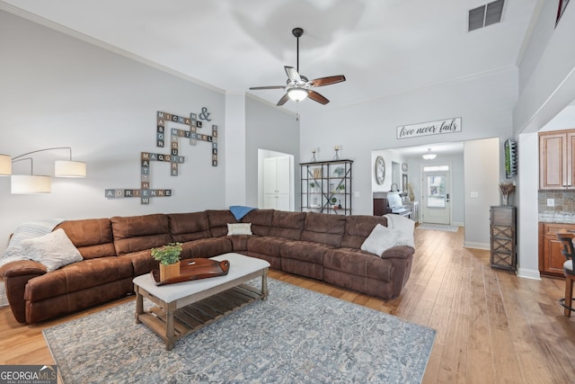 living room featuring light hardwood / wood-style floors, ornamental molding, and ceiling fan