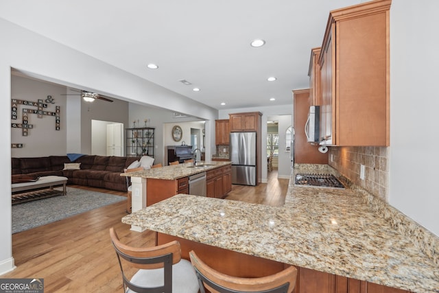 kitchen with stainless steel appliances, kitchen peninsula, light stone countertops, and sink