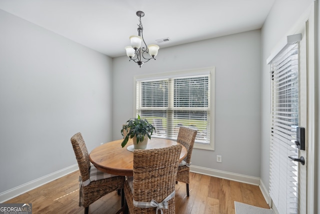 dining room featuring light wood-type flooring and an inviting chandelier