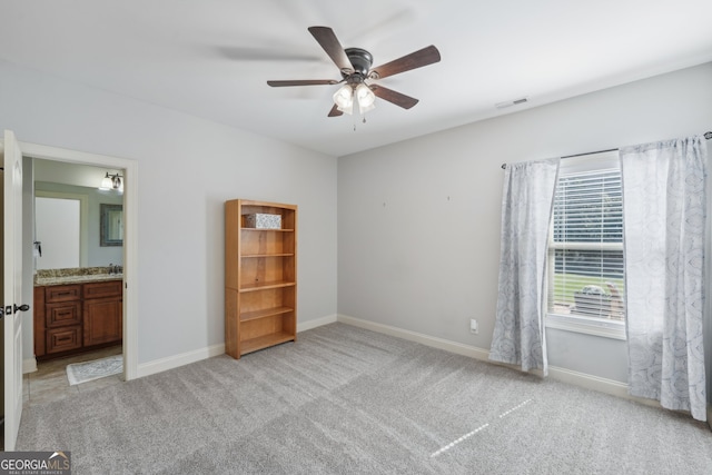 unfurnished bedroom featuring light carpet, ensuite bathroom, and ceiling fan