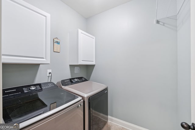 clothes washing area featuring light tile patterned flooring, washer and clothes dryer, and cabinets