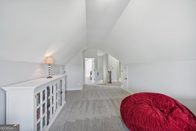 additional living space featuring vaulted ceiling and light carpet