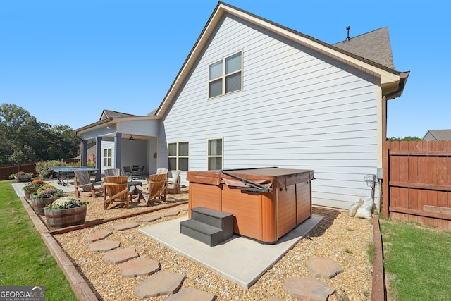 back of property featuring ceiling fan, a patio, and a hot tub