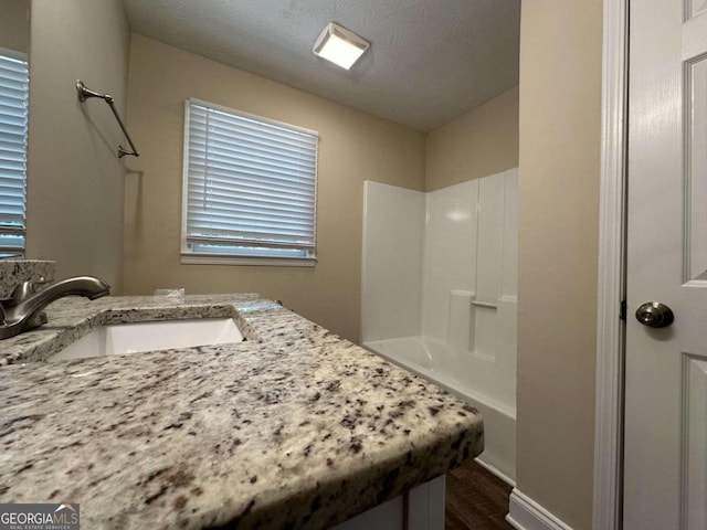 bathroom with vanity, a shower, a textured ceiling, and hardwood / wood-style flooring