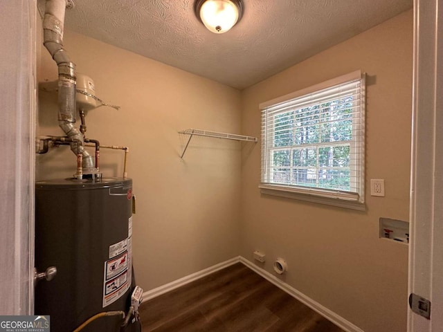 washroom featuring hookup for a washing machine, water heater, dark hardwood / wood-style floors, and a textured ceiling