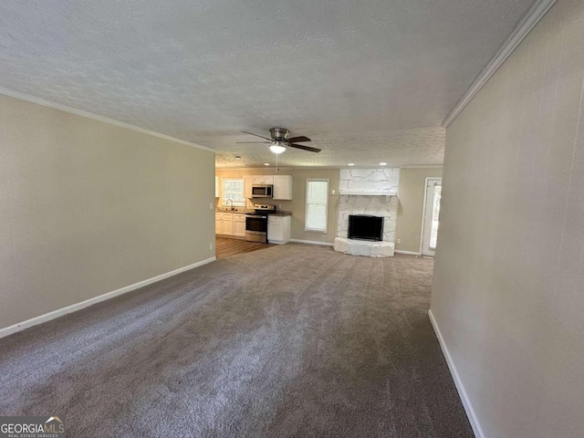 unfurnished living room featuring ceiling fan, crown molding, a fireplace, carpet, and a textured ceiling