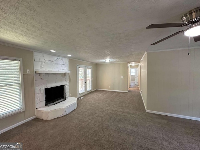 unfurnished living room with dark colored carpet, a fireplace, french doors, ornamental molding, and a textured ceiling