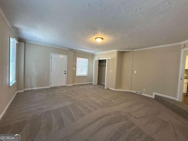 unfurnished room featuring crown molding, carpet, and a textured ceiling