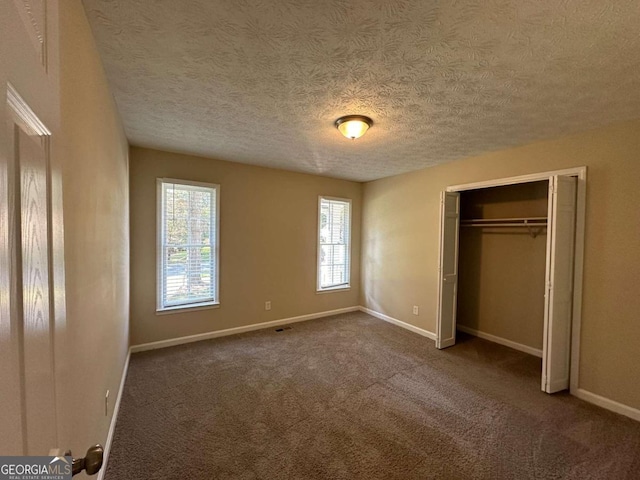 unfurnished bedroom with a textured ceiling, a closet, and carpet