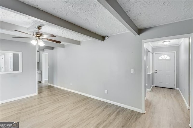 entryway featuring ceiling fan, beamed ceiling, light wood-type flooring, and a textured ceiling