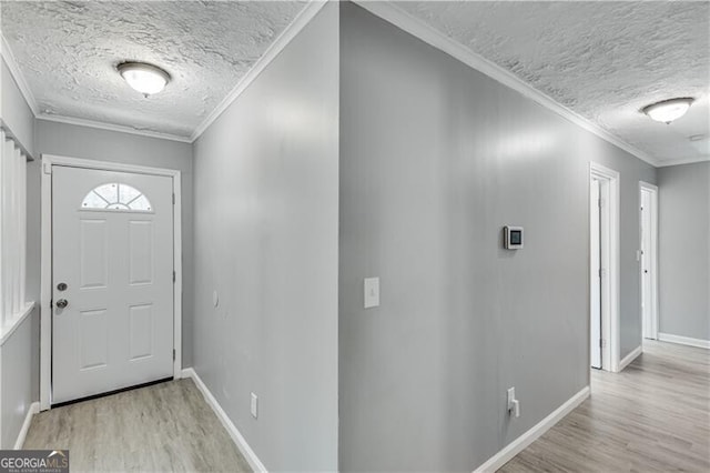 foyer with ornamental molding, light wood-type flooring, and a textured ceiling