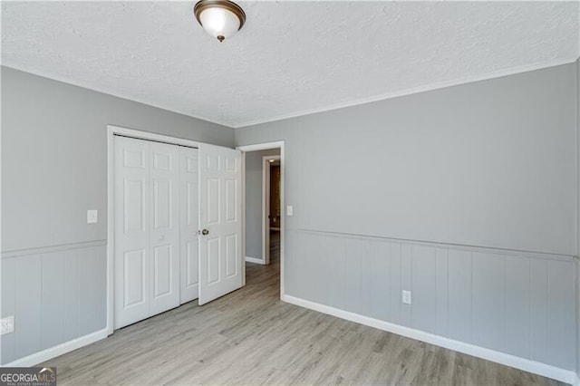 unfurnished bedroom with a textured ceiling, a closet, and light hardwood / wood-style floors