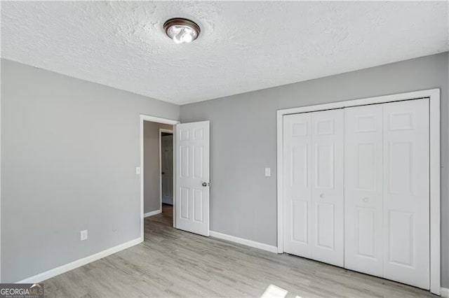 unfurnished bedroom featuring a closet, light hardwood / wood-style floors, and a textured ceiling