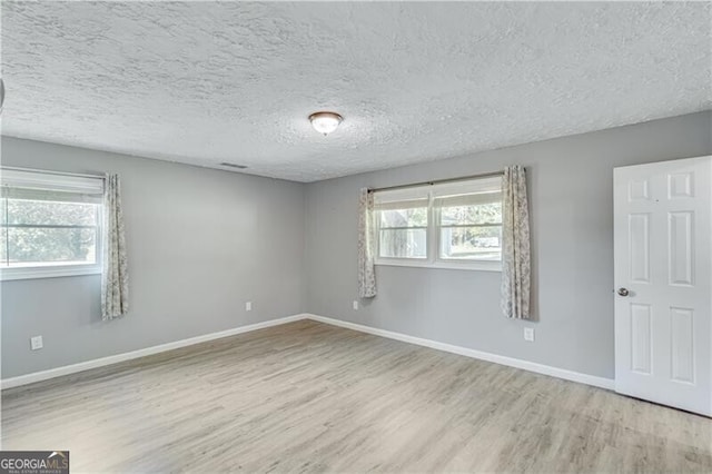 unfurnished room featuring light hardwood / wood-style flooring, a wealth of natural light, and a textured ceiling