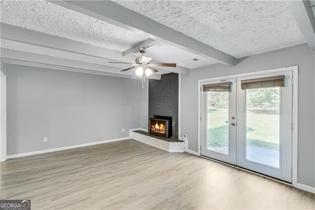 unfurnished living room featuring a fireplace, beamed ceiling, light hardwood / wood-style flooring, and a textured ceiling