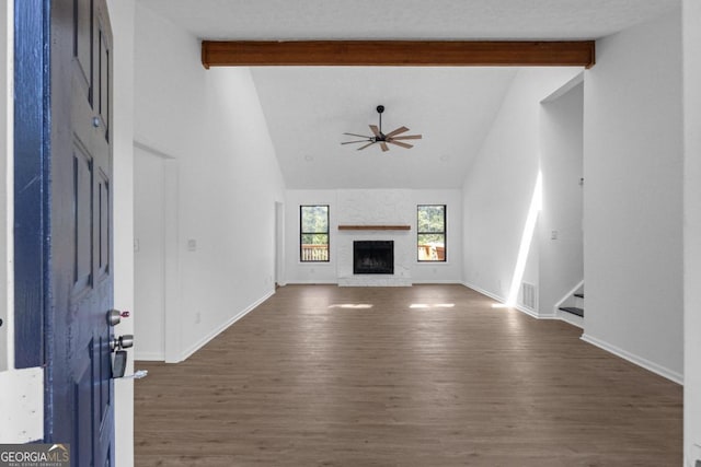 unfurnished living room with ceiling fan, beamed ceiling, high vaulted ceiling, a fireplace, and dark hardwood / wood-style flooring