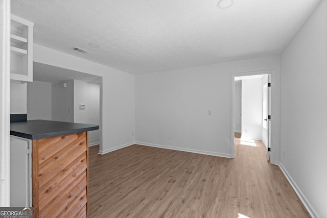 unfurnished living room featuring wood-type flooring, bar, and a textured ceiling