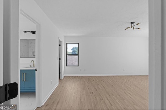 spare room featuring sink and light hardwood / wood-style flooring