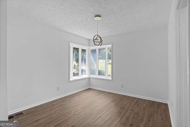 empty room with a textured ceiling and dark hardwood / wood-style flooring