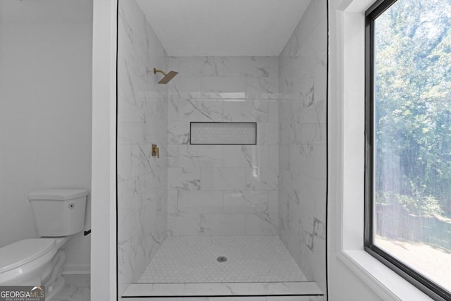 bathroom featuring a tile shower, plenty of natural light, and toilet