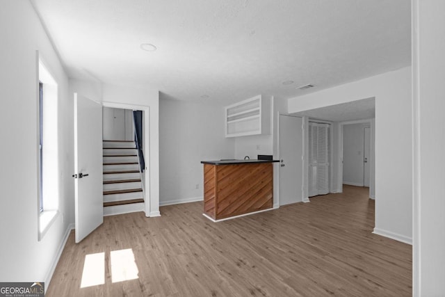 unfurnished living room featuring a textured ceiling and light hardwood / wood-style floors