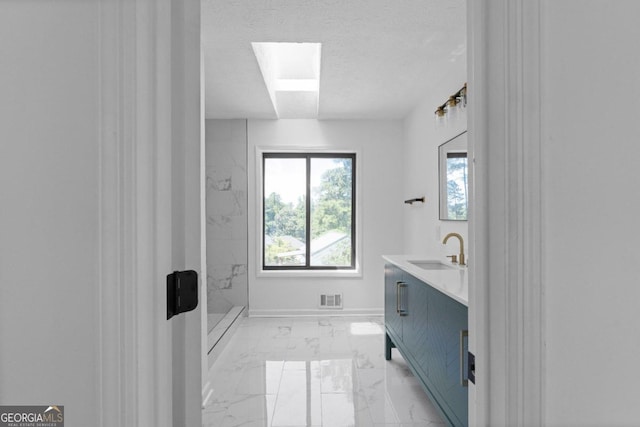 bathroom with a tile shower, vanity, and a textured ceiling