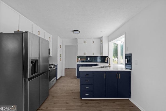 kitchen with hardwood / wood-style floors, sink, stainless steel appliances, white cabinets, and a textured ceiling