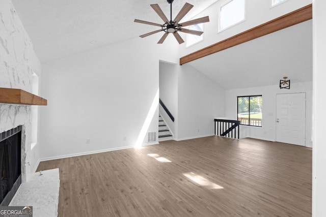 unfurnished living room with ceiling fan, beamed ceiling, hardwood / wood-style flooring, and high vaulted ceiling