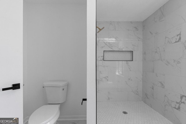 bathroom featuring a tile shower and toilet