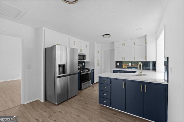 kitchen featuring blue cabinetry, stainless steel appliances, light hardwood / wood-style floors, and white cabinetry