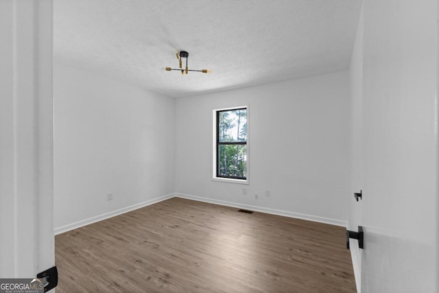 unfurnished room with hardwood / wood-style floors and a textured ceiling