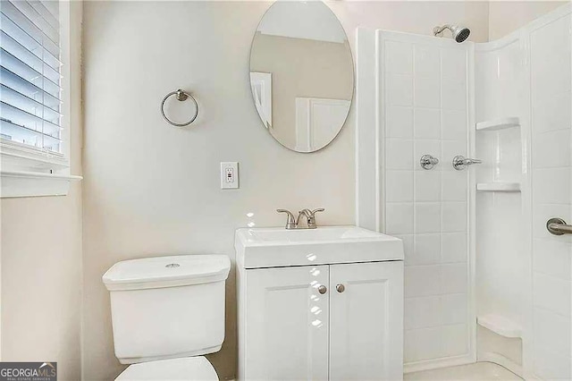 bathroom featuring a tile shower, vanity, and toilet