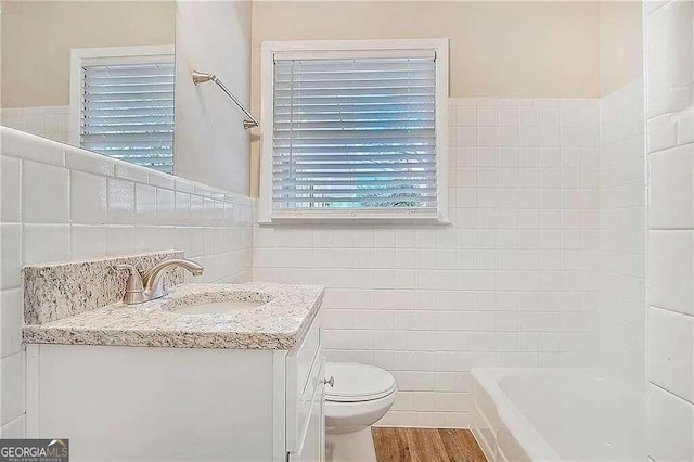 bathroom with hardwood / wood-style floors, toilet, vanity, and tile walls