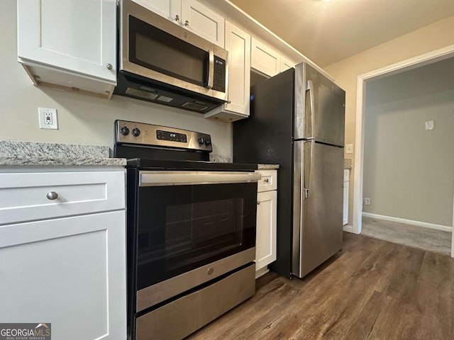 kitchen featuring light stone counters, white cabinets, stainless steel appliances, and dark wood-type flooring