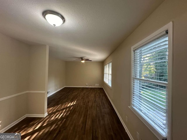 empty room with dark wood-type flooring, ceiling fan, and a textured ceiling