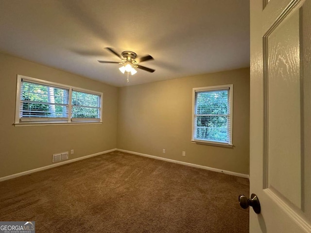 spare room featuring ceiling fan and dark carpet