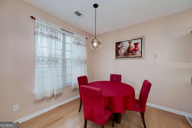 dining room featuring a chandelier, hardwood / wood-style floors, and a textured ceiling