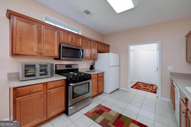 kitchen with light tile patterned floors, a textured ceiling, and stainless steel appliances