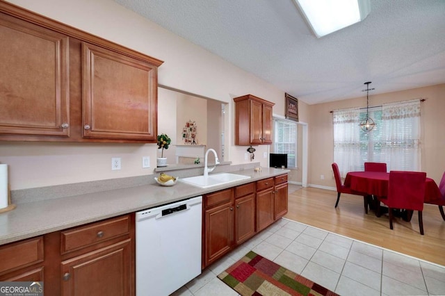 kitchen featuring a textured ceiling, white dishwasher, sink, hanging light fixtures, and light tile patterned flooring