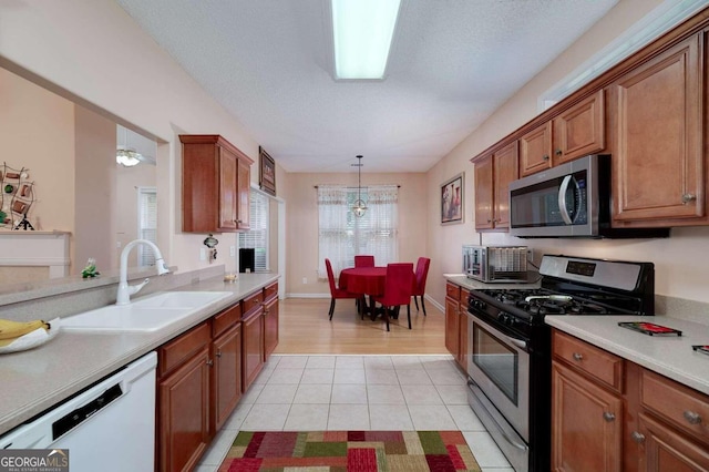 kitchen featuring sink, stainless steel appliances, pendant lighting, a textured ceiling, and light tile patterned flooring