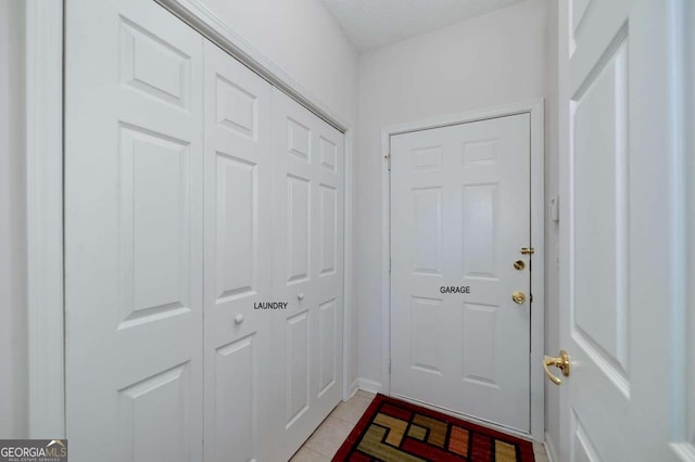 doorway to outside featuring light tile patterned floors and a textured ceiling