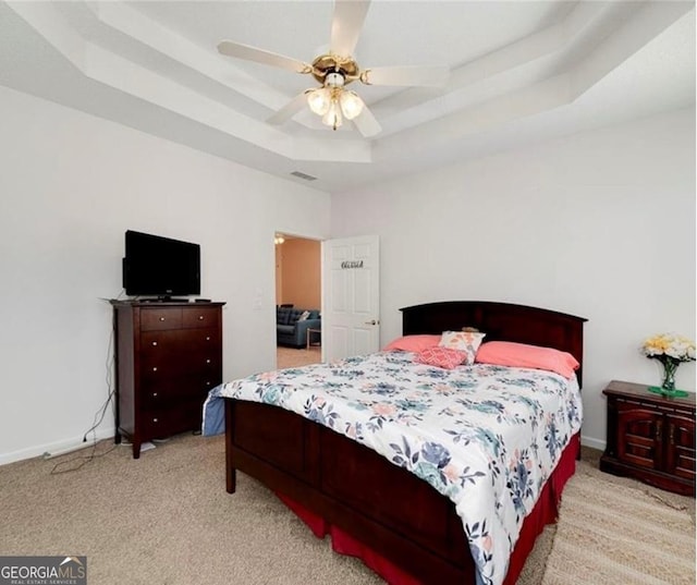 bedroom featuring ceiling fan, a raised ceiling, and light carpet