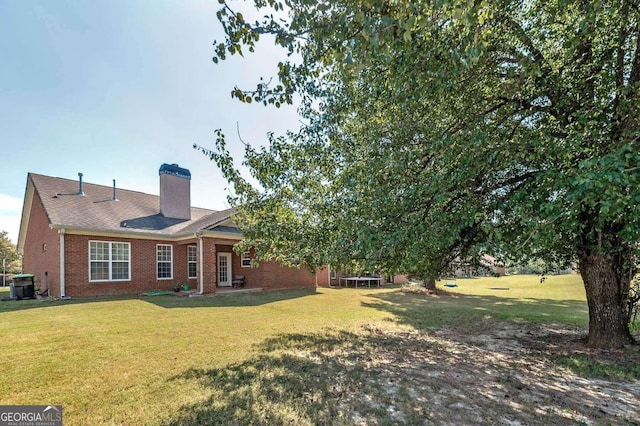 back of house with a yard, a trampoline, and cooling unit