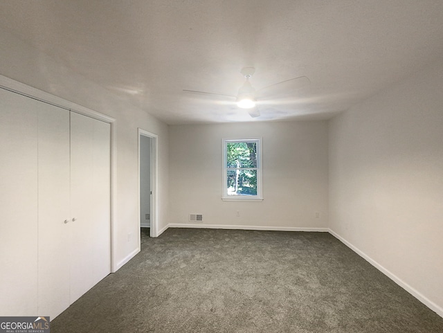 unfurnished bedroom featuring dark colored carpet, ceiling fan, and a closet