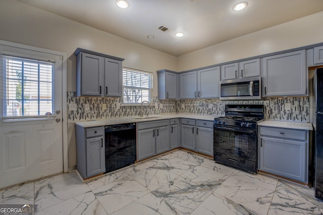 kitchen featuring tasteful backsplash, black appliances, sink, and gray cabinetry