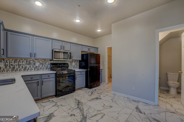 kitchen featuring gray cabinetry, light stone countertops, tasteful backsplash, and black appliances